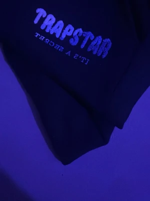 Svarta trapstar shorts strl M. - Svarta shorts med snören, äkta från trapstar med blå och vit detalj på loggan.
