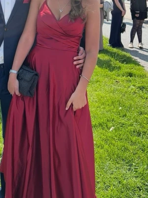 Vinröd balklänning  - Säljer en vinröd långklänning med smala axelband och omlottdetalj vid bysten. Klänningen har en v-ringad urringning. Även jätte fin knytning i ryggen(se sista bilden)  Perfekt för Bal!  Jag är 165 cm och har vanligtvis S i storlek.              Orginalpris  1500kr!