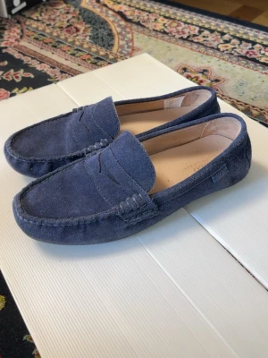 Mörkblå mockaloafers - Snygga mörkblå loafers i mocka med klassisk pennyloafers-design. Skorna har en mjuk ovandel och diskreta sömmar runt tån. Perfekta för en stilren look och passar till många outfits.