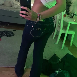 Äkta vintage Dolce & Gabbana lowwaist jeans - Säljer ett par mörkblå jeans från Dolce & Gabbana med snygga kontrastsömmar och DG-detalj på bakfickan. Jeansen har låg V formad midja som sitter väldigt snyggt men tyvärr så passar dom inte mig längre. Det var mina favoritbyxor.
