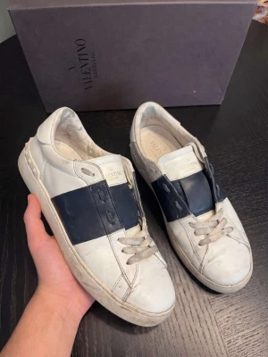 Valentino Garavani Open Sneakers – Vit/Svart | Strl 43 | 7/10 Skick - Valentino Garavani Open sneakers i vit med svart läder — ikonisk italiensk lyx med signatur Rockstud detaljer. 7/10 skick med normalt slitage, priset reflekterar skicket. ✅ Originallåda ✅ Skriv i DM för kvitto — vi håller det privat för att skydda köparens personliga information Storlek 43. Vi tar även emot byten och uppgraderingar. Vi reparerar, renoverar & rengör även skor — skriv i DM! 👟 📦 Spårad frakt, väl förpackad.