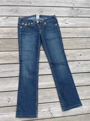 True Religion bootcut jeans blå - Pris går att diskutera🩷Snygga blå bootcut jeans från True Religion med klassiska kontrastsömmar och ikoniska fickdetaljer bak. Jeansen har låg midja och är tillverkade i denim med lätt slitning. Perfekta för dig som gillar en avslappnad men trendig stil.