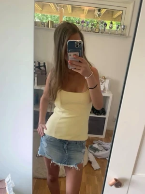 Låg midjad ljusblå jeanskjol - Trendig kort jeanskjol med låg midja  i ljusblå denim med slitna detaljer och fransig nederkant. Använd fåtal gånger. 