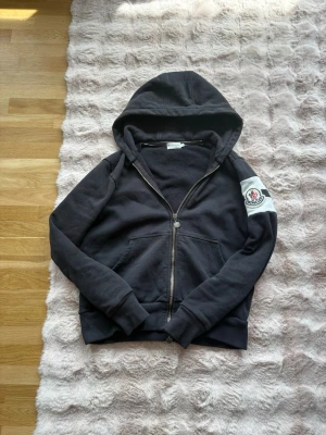 Svart hoodie från Moncler med dragkedja - Moncler hoodie med dragkedja köpt från merchsweden. Dragkedjan saknar 3 bitar men funkar att dra upp och ner.