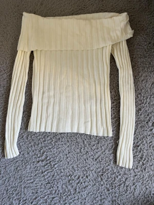 Offshoulder ribbad topp från H&M - Snygg offshoulder topp från H&M i ribbad, ljusvit bomullsmix. Långärmad modell med bred volangkant upptill som ger en trendig look. Perfekt att styla med jeans eller kjol för en cool vibe. Passar xs/s också!