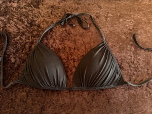 Svart trekantsbikini med knyt - Snygg svart trekantsbikini med knyt i nacken och ryggen. Klassisk modell med lätt rynkade kupor som ger en stilren look. Perfekt för stranden eller poolen.