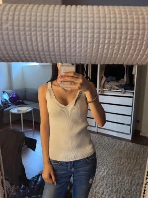 Ribbad beige linnetopp med v-ringning - köpt utomland, passar kanske xs-m då den är väldigt stretchig men står tyvärr ingen storlek! Säljer en ribbad beige linnetopp med v-ringning och breda axelband. Toppen har en slim passform och är perfekt att styla med jeans eller kjol. Materialet känns mjukt och stretchigt, vilket gör den superbekväm att bära.💕 