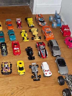Samling leksaksbilar i metall och plast - Stor samling leksaksbilar i olika färger och modeller, bland annat sportbilar, monstertrucks och bilar från Disney Cars. Bilarna är tillverkade i metall och plast och finns i flera färger som röd, gul, blå, orange och silver. Perfekt för bilentusiasten eller samlaren.