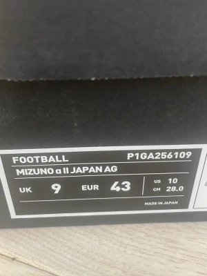 Mizuno α II Japan AG fotbollsskor 43  - Säljer ett par Mizuno α II Japan AG fotbollsskor i silver med svarta detaljer. Skorna har snörning och är tillverkade i syntetmaterial för optimal prestanda på planen. Perfekta för dig som vill sticka ut med stil och kvalitet på matchen. Nypris är 3800. Säljer pågrund ut av att de inte passade mig. Bara använd en träningsvecka