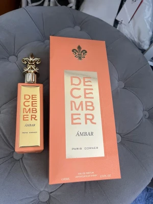 December Ámbar parfym Paris Corner - December Ámbar från Paris Corner är en Eau de Parfum med en lyxig orange och guldig flaska. Doften har toppnoter av anis, äpple och kokos, hjärtnoter av saffran, ros och plommon samt basnoter av kola, mossa, vanilj, amber, benzoin och cederträ. Köpte parfymen blind buy, inte min typ så vill bli av med den, jag har använt den 2-3 gånger
