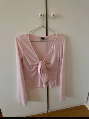 Ljusrosa långärmad topp med knyt - Supersöt ljusrosa långärmad topp från Gina Tricot med v-ringning och knyt framtill. Tunn och mjuk i materialet, perfekt till jeans