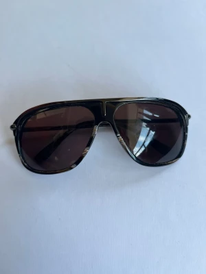 Tom Ford solglasögon  - Tom Ford solglasögon i fint skick. Inga större repor eller skador. Väldigt snygg och exklusiv modell med mörktonade glas. 100% äkta. Säljs utan fodral. Öppen för prisförslag 😊