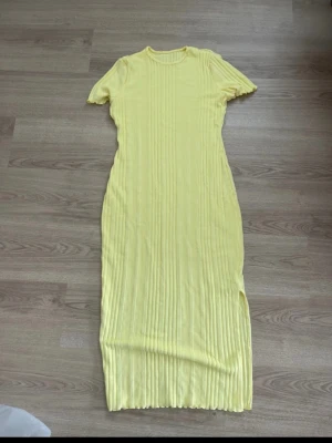 Gul ribbad långklänning - Säljer en ljusgul ribbad långklänning med korta ärmar och rund hals. Klänningen har en kroppsnära passform och är tillverkad i ett stretchigt material som ger en snygg siluett. Perfekt för sommarens alla tillfällen! Den är oanvänd ifrån Shein