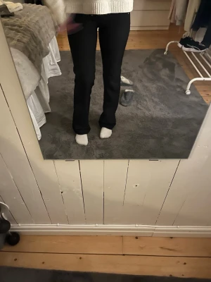 Svarta kostymbyxor med utsvängda ben - Snygga svarta kostymbyxor med utsvängda ben och klassiska fickor bak. Byxorna har en stilren och tidlös design som passar perfekt till en dressad look. Materialet ser ut att vara mjukt och följsamt för en bekväm känsla.