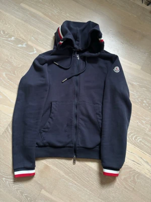 Marinblå Moncler hoodie  - Navy blue zip-hoodie från Moncler med ränder. Sitter bra o jävligt skönt. Måttligt använd. Skriv om du har några frågor!