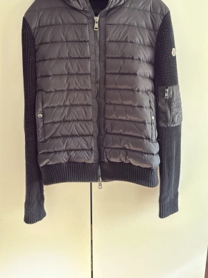 Moncler cardigan - Snygg svart cardiganjacka från Moncler. Nästintill ny använd fåtalet gånger. Inget slitage på jackan. Storlek XL men sitter bättre på en som bär L. Pris kan diskuteras vid snabb affär. 