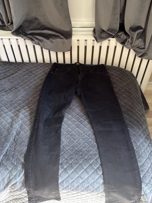Svarta jeans från Lee - Säljer ett par svarta jeans från Lee med klassisk femficksdesign och dragkedjegylf. Jeansen har raka ben och är tillverkade i ett slitstarkt denimtyg. Perfekta för en stilren och enkel look.