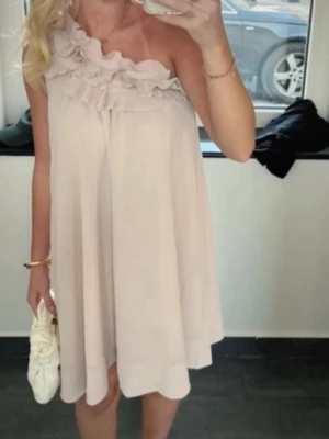Jättefin somrig klänning!🌸 - Supersöt ljus kortklänning med volangdetaljer och oneshoulder-design. Klänningen har en luftig passform och är perfekt för varma dagar. Tillverkad i ett mjukt och lätt material som ger en skön känsla. (Färgen är beige/rosa skulle jag säga!)