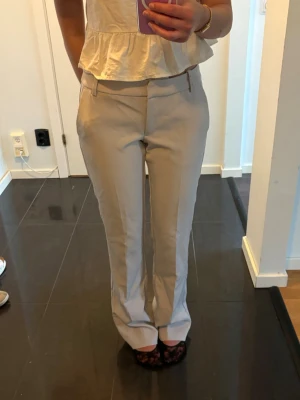 Grå lågmidjade kostymbyxor, raka ben - Snygga grå kostymbyxor med raka ben. Byxorna har hällor för skärp och fickor fram. Ganska långa i modellen, storlek 34 från bikbok.