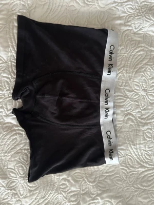 Svarta kalsonger från Calvin Klein - Svarta boxerkalsonger från Calvin Klein med klassisk grå resår och logga runt midjan. Snygg och enkel design som passar perfekt till vardags. Mjukt och stretchigt material för extra komfort.