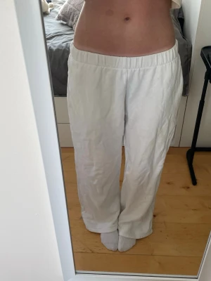 Vita mjukisbyxor - Säljer ett par vita mjukisbyxor med avslappnad passform och resår i midjan. Perfekta för varma dagar och enkla att styla med olika toppar. Byxorna har raka ben.
