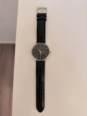 Svart klocka från GANT med läderband - Stilren klocka från GANT med svart urtavla och silverfärgade detaljer. Däremot behövs det byta nytt batteri. Kan även göra det men då kommer det kosta mer. Knappt använd. Har repor på 2-3 ställen men knappt synliga.
