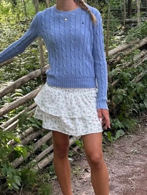 Nyskick Ralph lauren Ljusblå kabelstickad tröja Polo Ralph Lauren Stl xs  - Supersnygg ljusblå kabelstickad tröja från Polo Ralph Lauren med rund halsringning och diskret broderad logga på bröstet. Tröjan har ribbade muddar och är perfekt för en chill och stilren look. Materialet är mjukt och skönt bomullsgarn.