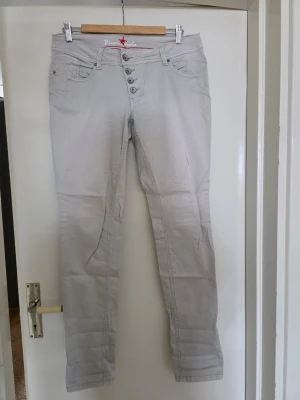 Ljusgrå jeans med knappar - Snygga ljusgrå jeans från Buena Vista med fem dekorativa knappar i gylfen och klassisk femficksdesign. Jeansen har smal passform och raka ben. Perfekta för dig som gillar en stilren och modern look.