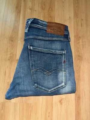 Replay Anbass jeans  - Snygga blåa Replay Anbass jeans med kontrastmönster i slim fit. Jeansens benslut har små slitsar. Midja 44cm, längd 95cm. Obs L storleken saknas men jag bedömer till L30 - men utgå efter angivna mått. JAG SKICKAR EJ FLER BILDER NÄR JAG BÄR JEANSEN! för bättre inblick i passformen rekommenderar jag att googla på modellnamnet. För storleksguide kolla måtten noggrant då jeansen alltid kan vara uppsydda heller krympta och jag ej tar emot returer :) 1,44