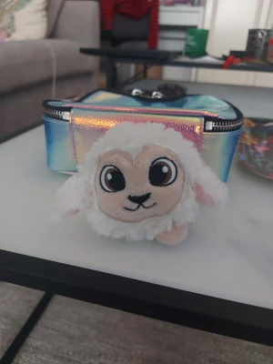 Söt mjukisdjur lamm - Ett gulligt mjukisdjur i form av ett litet lamm med stora svarta ögon och vit fluffig päls. Perfekt som present eller dekoration. Lammets ansikte är broderat och det är gjort i mjukt syntetmaterial.