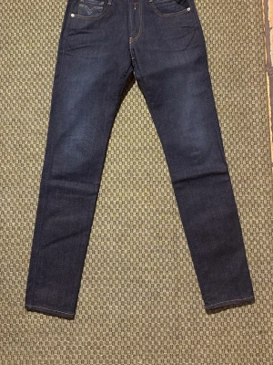 Replay anbass - Snygga mörkblå anbass jeans från Replay med klassiska fem fickor och kontrastsömmar. Jeansen är helt nya och har kvar alla taggar från butik. Hör av dig vid minsta fundering 🙌