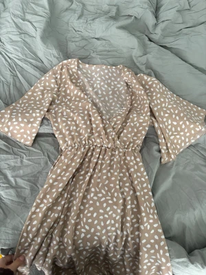 Supersöt klänning i beige - Säljer en klännibg i beige med vita pluttar på. Kort med band
