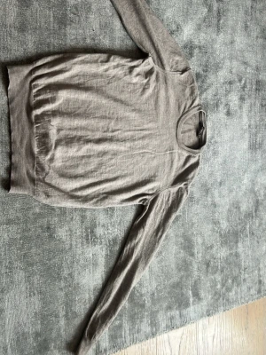 Beige tunn stickad tröja - En enkel och stilren beige stickad tröja med rund halsringning och långa ärmar. Tröjan har ribbade muddar vid ärmslut och nederkant, perfekt för lager på lager och en clean look.