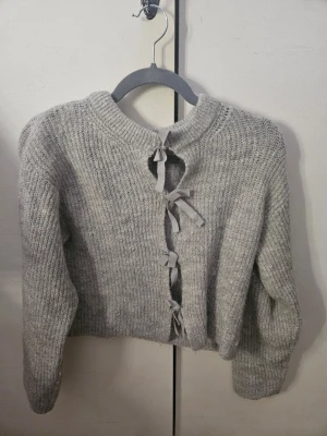 Grå stickad kofta med rosetter Gina Tricot - Supersöt grå stickad kofta från Gina Tricot med tre dekorativa rosetter framtill istället för knappar. Perfekt för lager på lager och en mysig look. Använd ett fåtal gånger men i mycket bra skick. 💓