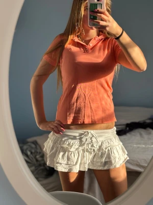 Korallfärgad tröja - Snygg korallfärgad pikétröja från Abercrombie & Fitch med klassisk krage och knappar framtill. Tröjan är kortärmad och har en liten broderad logga på bröstet. Perfekt till jeans eller kjol för en fräsch look.