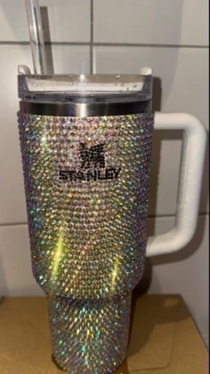 40oz Stanley glittrig mugg med sugrör - Säljer en stor Stanley-mugg med handtag och sugrör, täckt av glittrande strass i regnbågsfärger. Muggen har ett genomskinligt lock och vit plastdetalj på handtaget. Perfekt för dig som vill ha något extra bling till drycken.   (Minns inte om den vart använd en enstaka gång eller inte! Skicket är som nytt!🙌 Nyrpis: 4000kr från etsy)