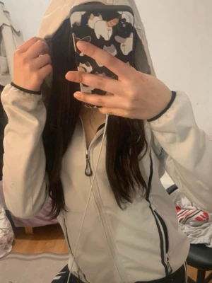 Vit hoodie med svarta detaljer - Säljer en vit hoodie med svarta dragkedjor och detaljer. Hoodien har huva med dragsko och fickor på sidorna. Perfekt för en avslappnad och sportig stil. Passar dig som gillar enkel men snygg design.