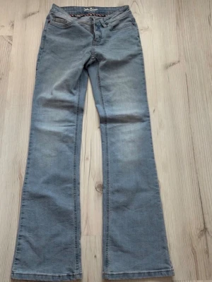 Ljusblå bootcut jeans John Baner - Säljer ett par ljusblå bootcut jeans från John Baner. Klassisk femficksmodell med normal midja och utsvängda ben. Jeansen har snygga slitningar och är tillverkade i mjuk denim med kontrastsömmar. Perfekta för en avslappnad och trendig look.