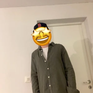 Grön skjorta med knappar - Snygg grön linne skjorta med klassisk krage och vita knappar hela vägen. Skjortan har lång ärm och en loose passform som ger en chill vibe. Perfekt att bära över en t-shirt för en avslappnad stil. Materialet linne, vilket gör den skön och lätt.