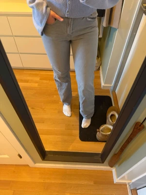 Grå jeans med stjärndetalj bak - Säljer populära  grå jeans från designbysi med rak passform med grön stjärna på bakfickan. Jeansen har klassiska fickor fram och bak, och är gjorda i denim. Perfekt för dig som vill ha något unikt och trendigt i garderoben. Säljes pga för små.  I fint skick men behöver strykas.