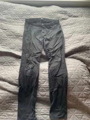Svarta chinos från H&M - Säljer ett par svarta chinos från H&M med klassisk rak passform. Byxorna har knapp- och dragkedjestängning, två sidofickor fram och två bakfickor. Tillverkade i mjukt bomullsmaterial som är sköna att bära hela dagen.