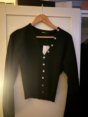 Svart ribbad kofta från Gina Tricot - Svart kofta från Gina Tricot med detaljer och V-ringning. Koftan har silvriga knappar längs hela framsidan💞