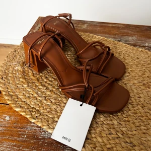 Bruna strappy sandaler från Mango  - Snygga bruna sandaler från Mango MNG med tunna remmar och fyrkantig tå. Klackarna är medelhöga och sandalerna har en elegant, minimalistisk design. Tillverkade i konstläder med stilrena detaljer och justerbar rem runt ankeln. Klacken 6,5cm Nypris529kr helt oanvända med låda och prislapp kvar på🤎
