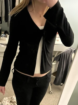 Svart långärmad topp med knyt - Trendig svart långärmad topp från H&M med snygg knytning framtill. Toppen har en croppad passform och är tillverkad i mjukt, stretchigt material! Storlek XS❣️