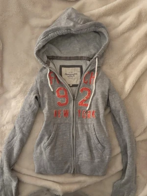 vintage yk2 abercrombie zip up hoodie - vintage grå abercrombie & fitch zip kofta med orange tryck. stl L men väldigt liten i storlek! mer som en S, fint skick!💞