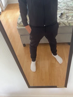 Svart/mörkblå Hugo boss sett - Säljer ett svart/mörkblå sett  från Hugo boss med dragkedja framtill och två fickor. Hoodien har justerbar huva med snören och diskret BOSS-logga på bröstet. Med matchande byxor till. Tillverkad i mjukt material som känns skönt mot huden. Perfekt för en chill och stilren look. Köpt för 2300 men säljer för 2000 men pris kan diskuteras vid snabbt köp. Kan köpas enskilt. Koftan för 1000kr. Byxorna för 1000kr. Men pris kan diskuteras som sagt.