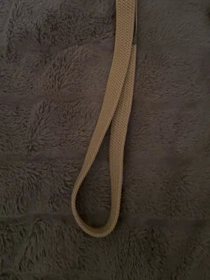 Beige flätat bälte  - Snyggt beige bälte med flätad design som ger en avslappnad och trendig look. Perfekt att styla till jeans eller kjol för en enkel men cool outfit. Tillverkat i mjuk bomull som känns bekvämt hela dagen.