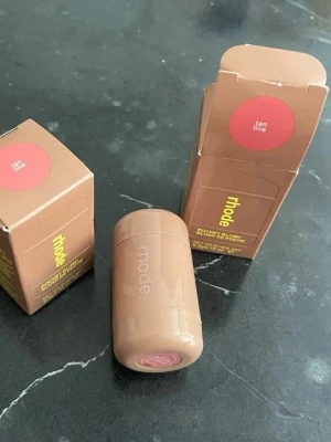 Rhode Pocket Blush Tan Line - Krämrouge från Rhode i nyansen Tan Line. Kommer i en kompakt, cylinderformad förpackning i beige plast med lock. Enkel att ta med i väskan och perfekt för att ge kinderna en naturlig, solkysst ton. Färgen är varm och brunrosa.