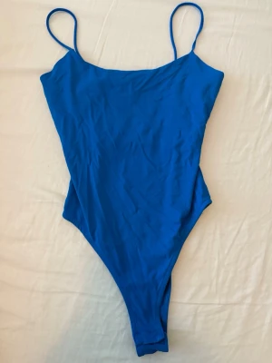Body ifrån Zara i storlek S.  - Snygg blå body från Zara med tunna axelband och enkel, stilren design. Materialet är stretchigt och följsamt. Klassisk urringning och hög skärning vid benen ger en modern look. Lite knopprigt material syns kanske på bilderna. Använts några gånger. 