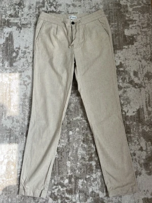 Beige linnebyxor  - Beige linnebyxor från John Henric med rak passform. Lite mer slimfit men passar bra till snygg skjorta eller T-shirt. 